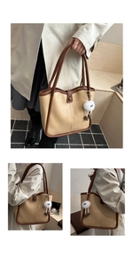 Detail of the cream faux leather tote bag showing the plush monster charm and brown trim