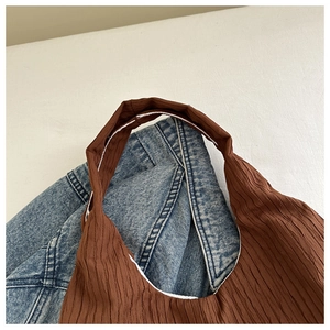 Vue détaillée du sac cabas plissé marron posé sur une veste en jean bleue