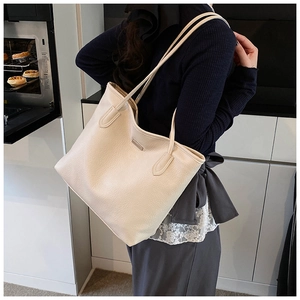 Detail showing creamy white pebbled leather texture and metal accent on tote bag