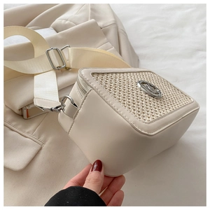 Detail of beige crossbody bag with leather texture and woven fabric patchwork design
