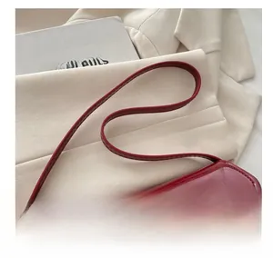 Detail of red patent leather handbag with gold twist lock and elegant thin strap