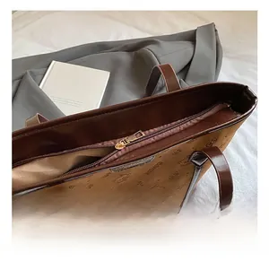 Detailed macro view of the golden metal zipper closure on the brown leather tote bag