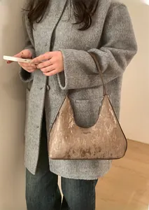 Borsa hobo plissettata bronzo metallizzato abbinata a un cappotto grigio per look invernale