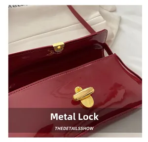 Close-up of golden metal twist lock on a glossy red patent leather shoulder bag