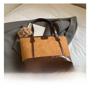 Close-up of color-block tote bag with cat embossed pattern and brown plush bear charm