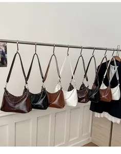 Dettaglio di borse minimaliste in nero, marrone e bianco con catena in metallo