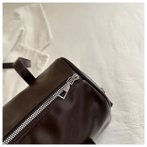 Detail view of smooth silver metal zipper and dark brown faux leather texture of the bag