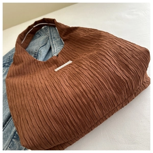 Détail du sac cabas plissé marron avec étiquette Fashion et texture rayée unique