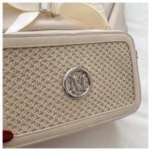 Detail of creamy white crossbody bag showing woven texture and silver metal M logo