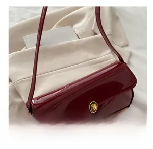 Detailed view of glossy red patent leather shoulder bag with gold metal twist lock buckle
