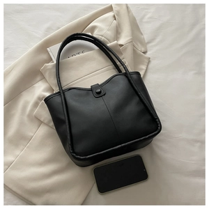Close-up of minimalist black vintage tote bag with premium matte leather and metal clasp
