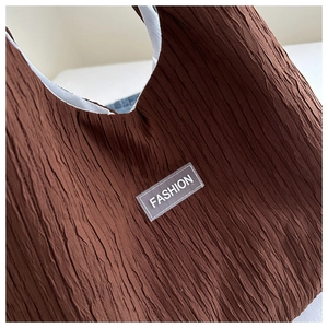 Gros plan détaillé d'un sac cabas plissé marron foncé avec une étiquette de mode