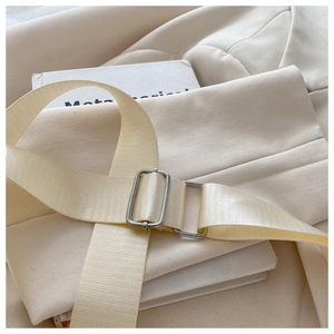 Close-up of beige nylon shoulder strap with a polished silver square metal buckle