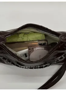 Internal view of dark brown patent leather bag showing daily essentials capacity