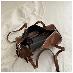 Top view of brown cylinder bag interior with phone and wallet on velvet background