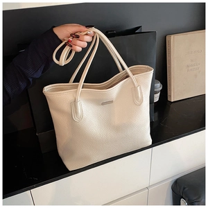 Close-up of cream white lychee texture leather tote bag with silver metal logo plate