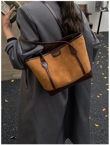 Detail of a brown tote bag with embossed cat patterns and leather straps on a model