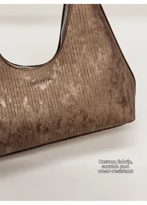 Detailed close-up of textured scratch-resistant brown fabric on a stylish shoulder bag