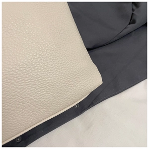 Macro shot of ivory pebbled leather texture with neat stitching on a designer tote bag