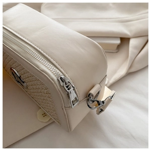 Close-up of beige crossbody bag showing stitched faux leather and straw texture detail
