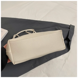 Detail shot of beige tote bag base showing premium lychee grain faux leather and stitching