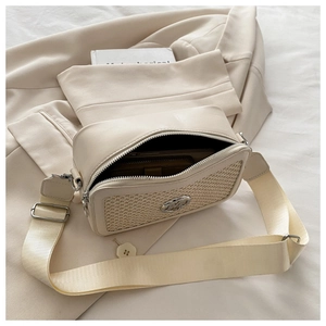 Detail view of cream shoulder bag with woven texture, metal logo and wide strap