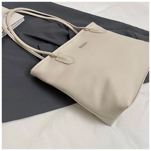 Detail of cream pebbled leather tote bag featuring minimalist silver metal hardware