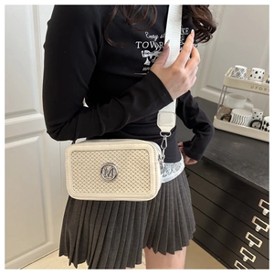 Detail of woven crossbody bag with cream leather trim and round metal M logo
