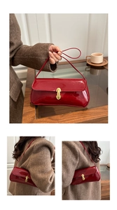 Detail of red patent leather baguette bag with gold buckle on herringbone coat