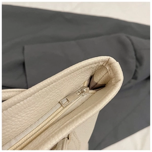 Detailed macro view of beige pebble grain leather texture and silver metal zipper