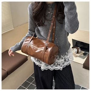 Brown glossy leather cylinder crossbody bag with stylish metallic eyelet shoulder strap
