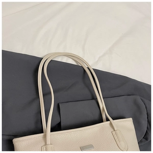 Close-up of cream white tote bag with lychee texture and silver metal detail
