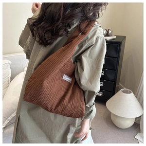 Detail of dark brown pleated fabric shoulder bag with FASHION label on model