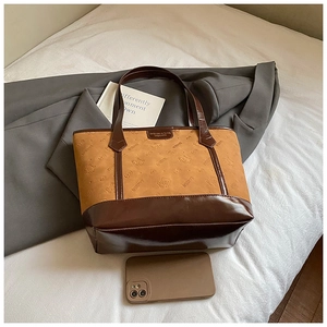 Close-up of brown patchwork tote bag with embossed cat patterns and metallic logo