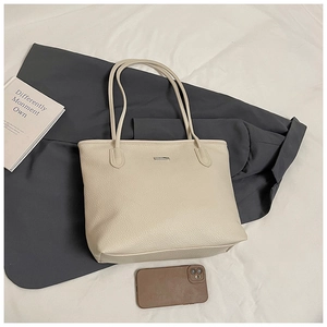 Détail du sac cabas crème avec texture litchi et plaque de logo en métal rectangle