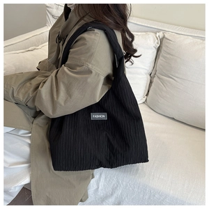 Détail du sac cabas plissé noir avec étiquette de mode sur un tissu texturé