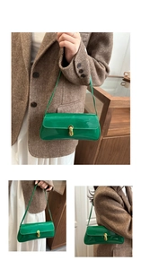 Detail of green patent leather baguette bag with gold metal buckle and glossy finish