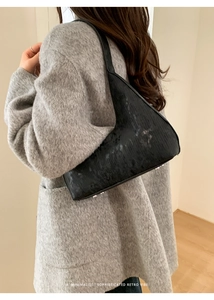 Dettaglio della borsa sottobraccio nera retrò con texture verticali e borchie in metallo