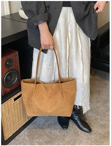 Close-up of brown suede tote bag featuring central vertical stitching and long shoulder strap