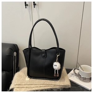 Detail of black matte PU leather tote bag featuring a vertical embossed design and a cute plush charm