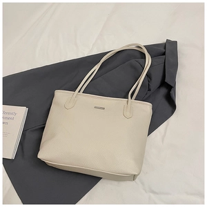 Macro view of cream-colored lychee pattern leather tote bag with metallic logo detail