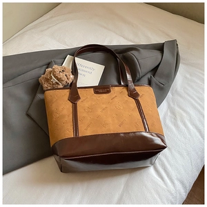 Close-up of camel suede tote bag with brown leather contrast and embossed cat logo detail