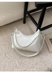 Detail of white half-moon shoulder bag with silver chain and matte faux leather texture
