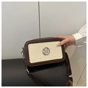 Detail of the woven texture and metal M logo on the brown leather crossbody shoulder bag