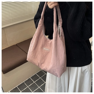 Close-up of pink pleated fabric tote bag featuring a stitched fashion label detail