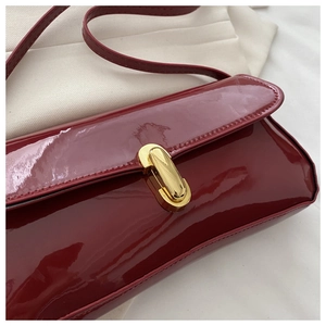 Detailed macro shot of the glossy wine red patent leather and gold capsule lock buckle