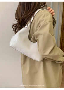 Dettaglio della borsa a spalla bianca a mezzaluna con trama spazzolata indossata con un trench beige