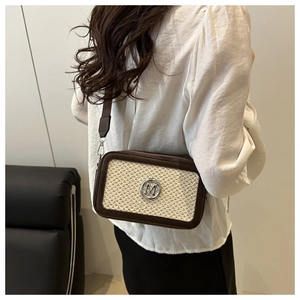 Detail of tweed crossbody bag with silver M logo and wide strap shown on a model