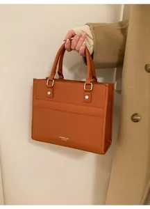 Dettaglio borsa shopper arancio-marrone in pelle a grana con logo stampato alla moda