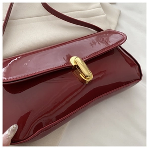 Macro view of the wine red patent leather shoulder bag with a gold metal twist lock